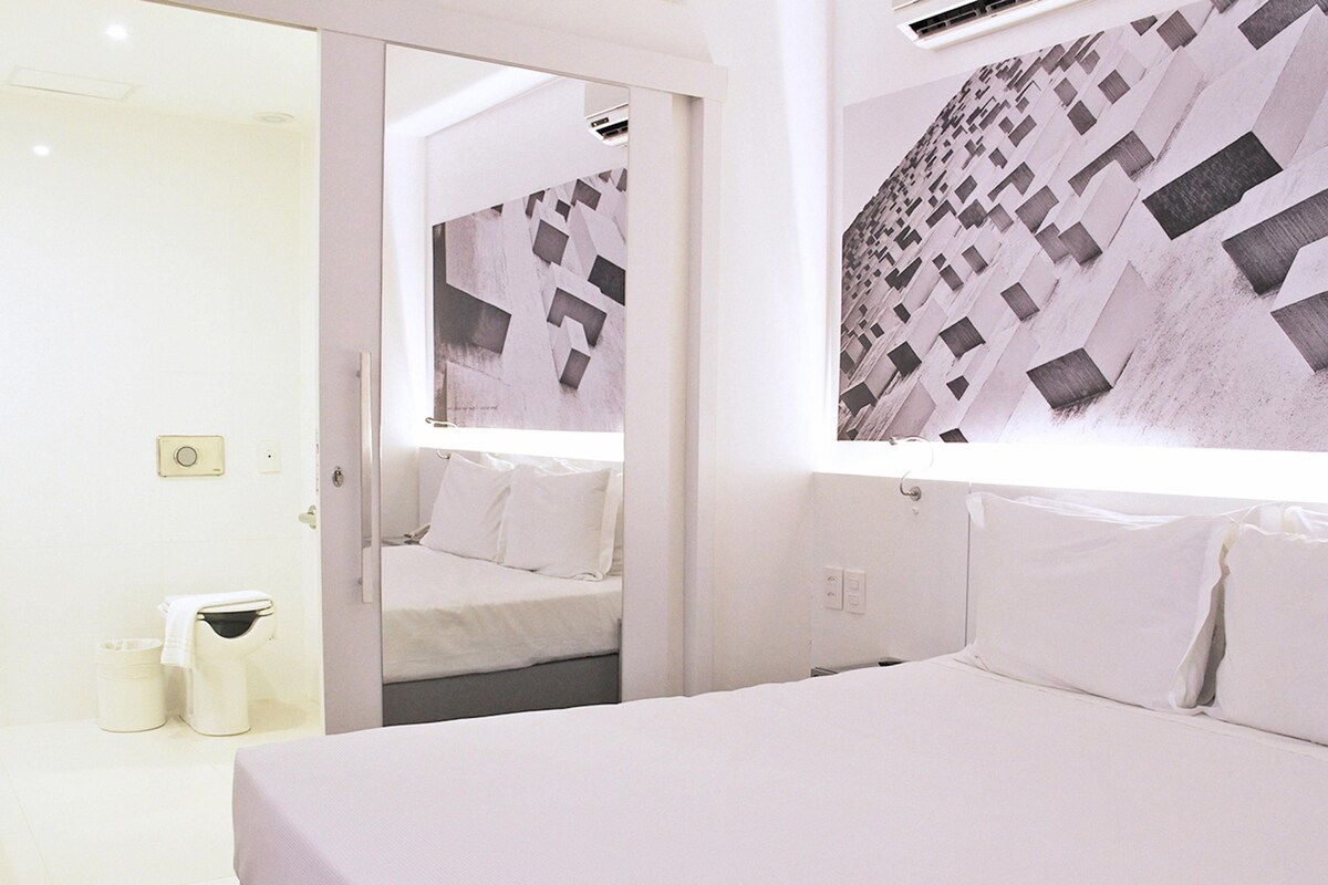Ein Hotelzimmer mit Bett, Spiegel und Wand mit geometrischem Muster.