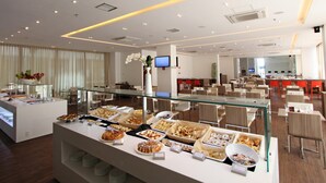 Un espace buffet proposant divers plats, une vitrine réfrigérée et un coin salon avec des tables et des chaises.