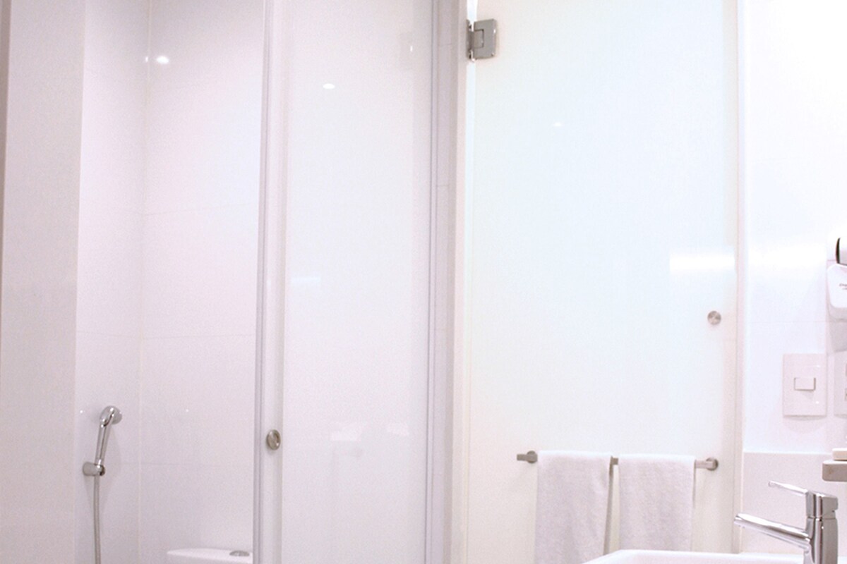 Een moderne badkamer met een douchecabine, een toilet met een handdoek en een grote wastafel met spiegel.