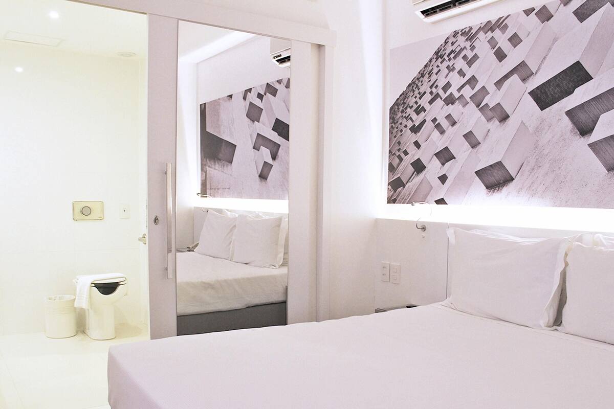Ein Hotelzimmer mit Bett, Spiegel und Wand mit geometrischem Muster.