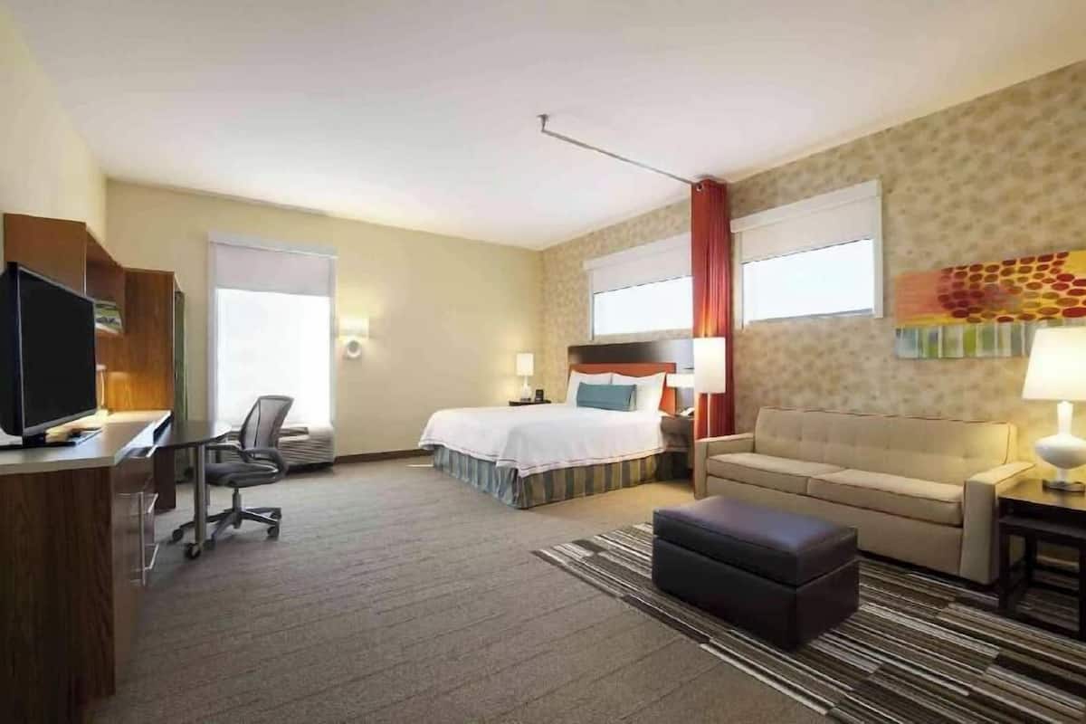 Una habitación de hotel con una cama, un escritorio con computadora, un sofá y un televisor.