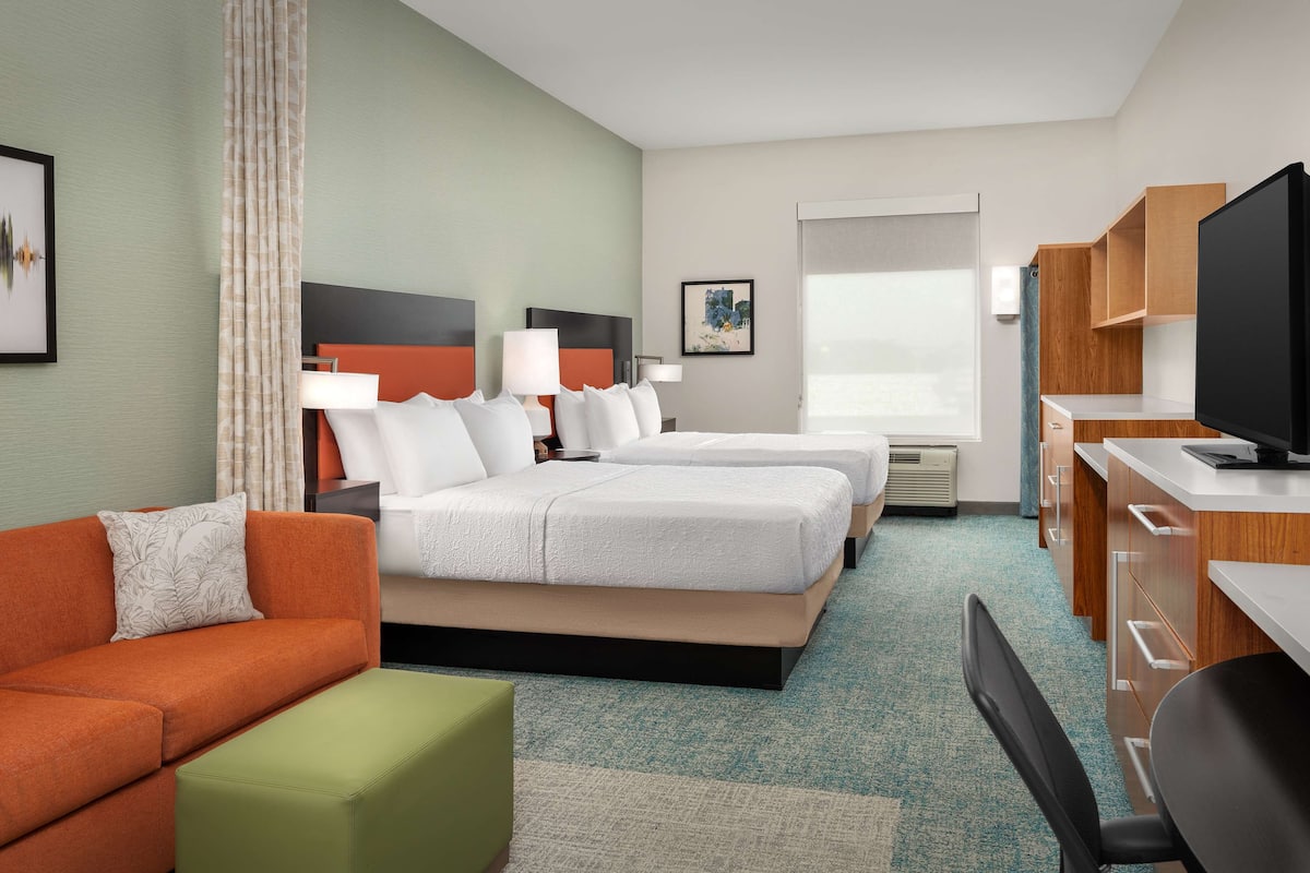 Una habitación de hotel con cama, sofá, escritorio y televisión.