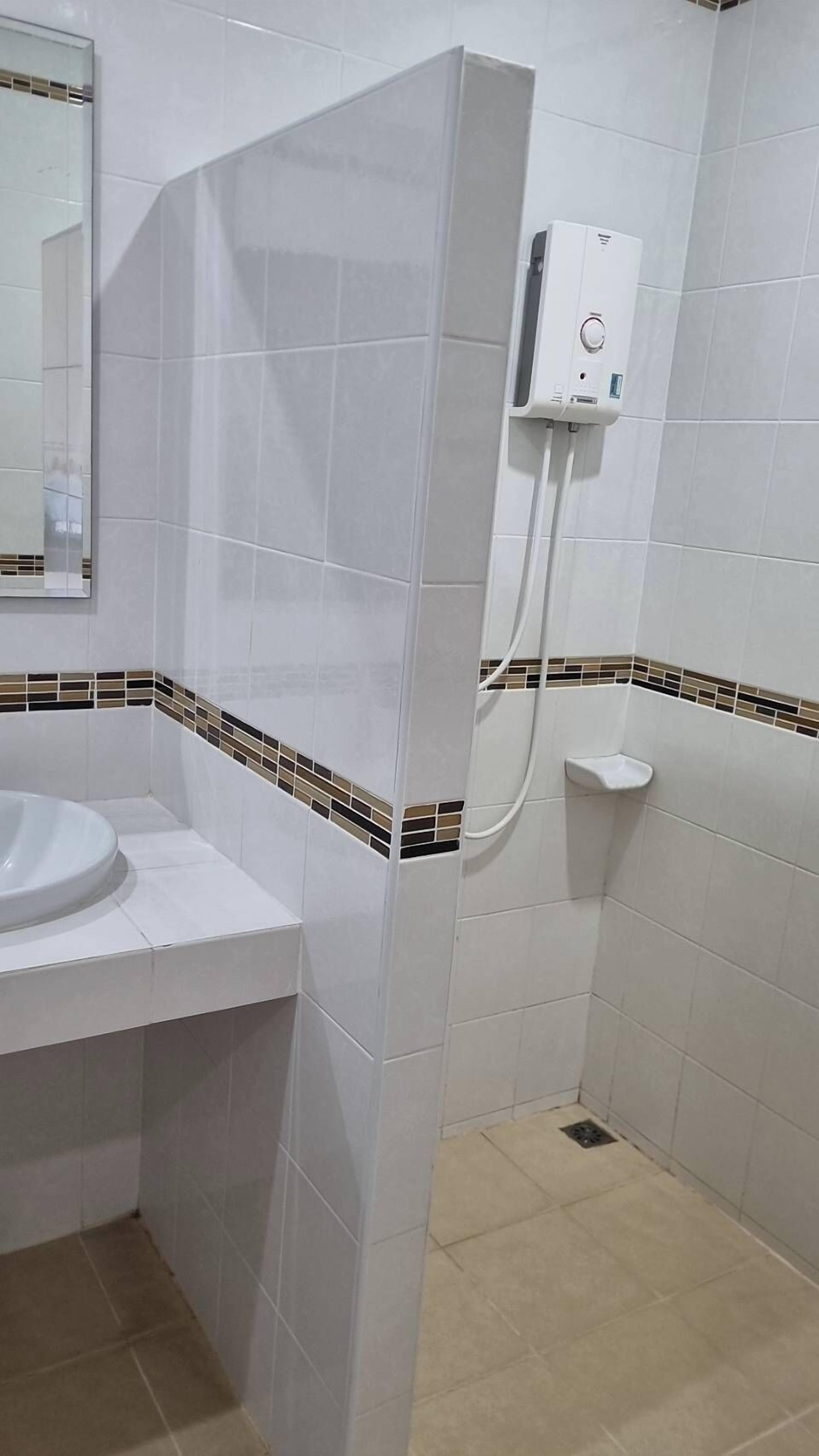 Une salle de bain avec un lavabo blanc, un espace douche et un sol carrelé.