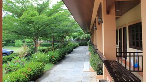A covered walkway with a bench, surrounded by greenery and a car parked nearby. - Kanlaya Park Apartment Hotel (Koh Samui)