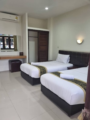 A hotel room with two beds, a mirror, a window with a view, and an air conditioning unit. - Kanlaya Park Apartment Hotel (Koh Samui)