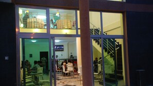 A modern building with a glass facade, a staircase, and a dining area with tables and chairs. - Addis Amba Hotel (Bahir Dar)