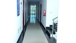 A long, narrow hallway with a fire extinguisher mounted on the wall, a staircase on the right, and a door at the end. - Addis Amba Hotel (Bahir Dar)