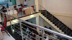 A multi-level dining area with tables and chairs, a staircase, and a television on the wall. - Addis Amba Hotel (Bahir Dar)