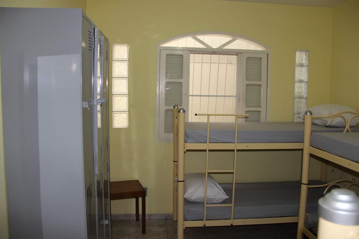 A bunk bed room with a window, a desk, and a cabinet.