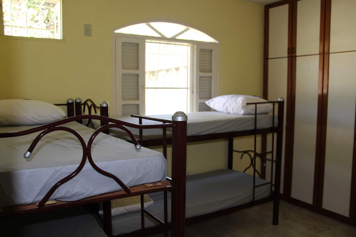 A room with three bunk beds, a wardrobe, and a window with shutters.
