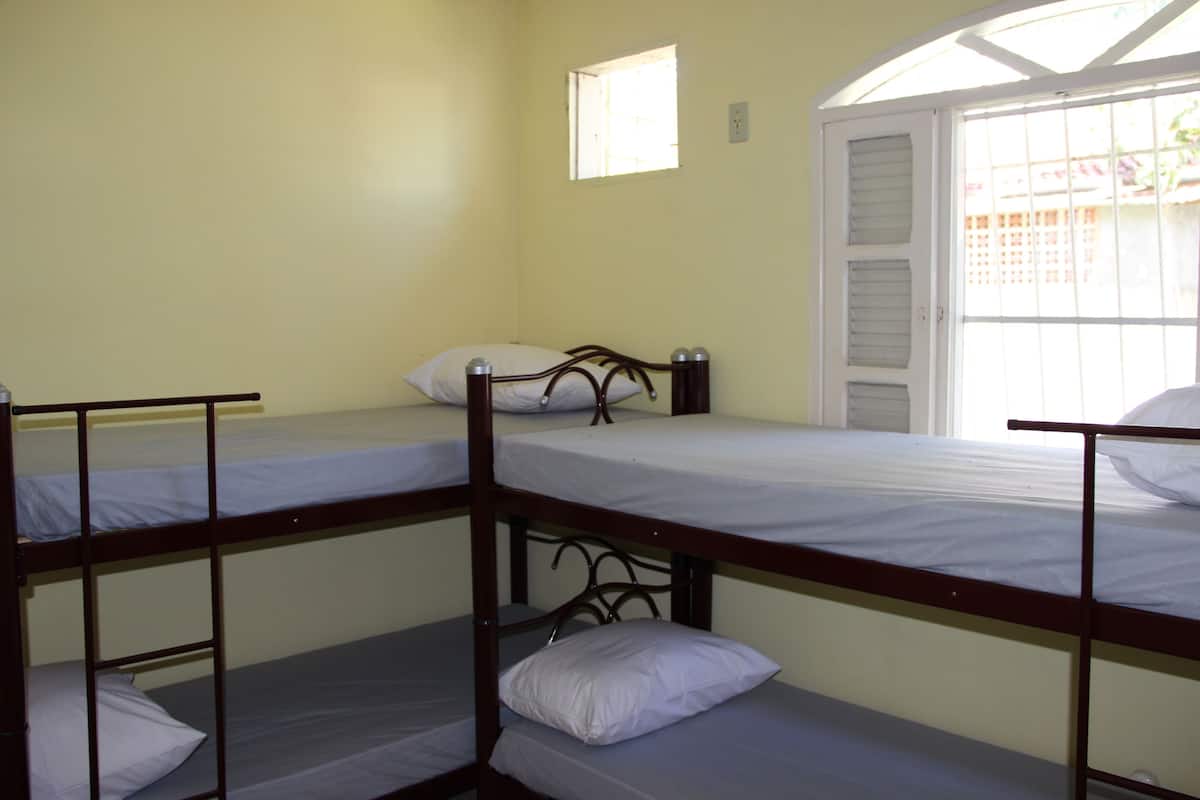 A dormitory room with bunk beds, a window, and a door.