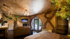 A cozy room with a unique tree-shaped ceiling, a comfortable sofa, a bed, and a television displaying a birthday message. - Eureka Springs Treehouses, Hobbit Caves & Castles (Eureka Springs)