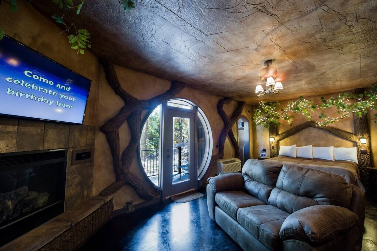 Una habitación acogedora con chimenea, un sofá de cuero y un ventanal grande.