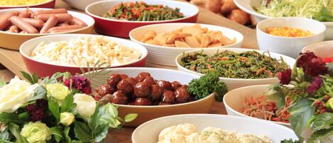 A buffet table with various dishes and a floral centerpiece.