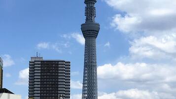 A tall tower with a lattice structure, surrounded by urban buildings and vehicles.