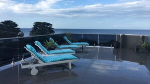 A rooftop terrace with sun loungers and a view of the sea. - Starhaven Retreat (Indented Head)