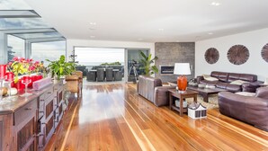 A spacious living room with a wooden floor, leather sofas, a dining area with a glass-top table, and a view of the outdoors. - Starhaven Retreat (Indented Head)