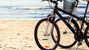 A bicycle with a basket and fenders parked on a sandy beach with the ocean in the background. - Starhaven Retreat (Indented Head)