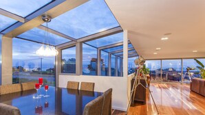 A modern dining area with a glass ceiling, a wooden floor, and a view of the outdoors. - Starhaven Retreat (Indented Head)