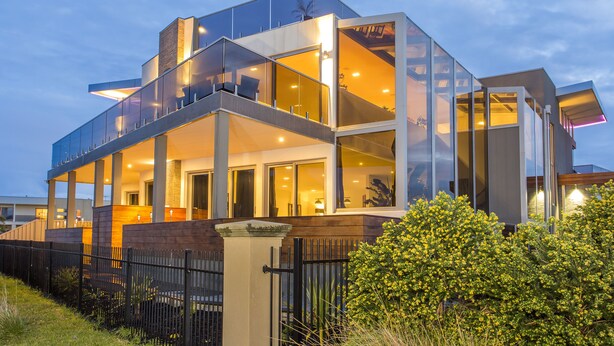 A modern, multi-story house with large glass windows, a balcony, and a well-lit interior. - Starhaven Retreat (Indented Head)
