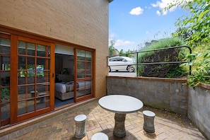 A patio with a round table and stools, a sliding glass door leading to a room, and a white car parked outside. - Hideaway on George (Launceston)