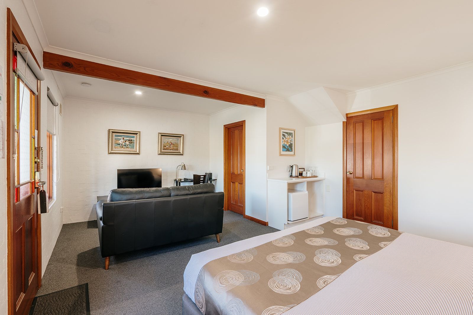Une chambre à coucher comprenant un lit, un canapé, un bureau et un petit réfrigérateur.
