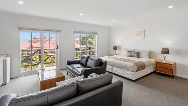 A modern bedroom with a large bed, a leather sofa, and a small table.