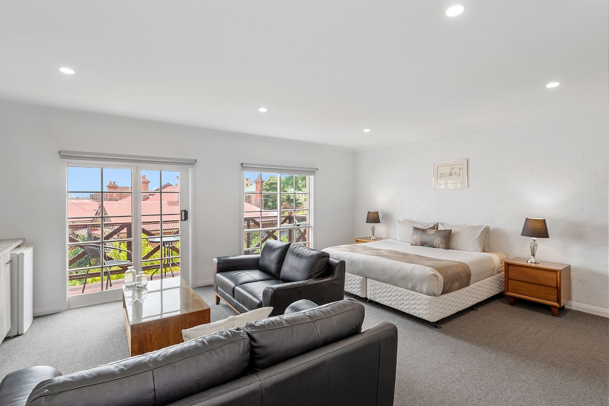 A modern bedroom with a large bed, a leather sofa, and a small table.