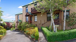 A traditional building with a green roof, a wooden staircase, and a well-maintained garden. - Hideaway on George (Launceston)