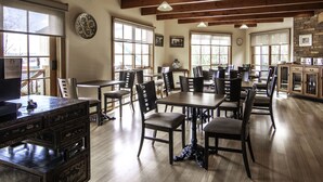 A spacious dining area with multiple tables and chairs, wooden floors, and large windows allowing natural light. - Hideaway on George (Launceston)