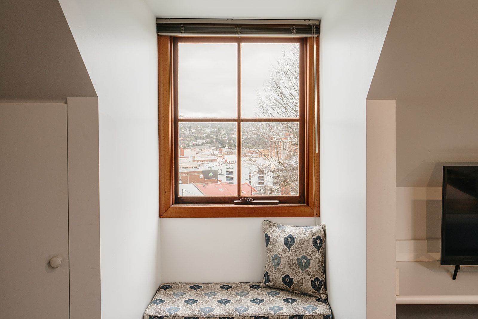 A room with a window, a sofa, and a television.