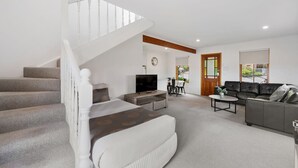 A spacious living area with a staircase, a sofa set, a television, and a coffee table.