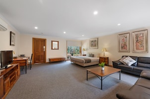A spacious living room with a sofa, a coffee table, a TV, and a door leading to a balcony.