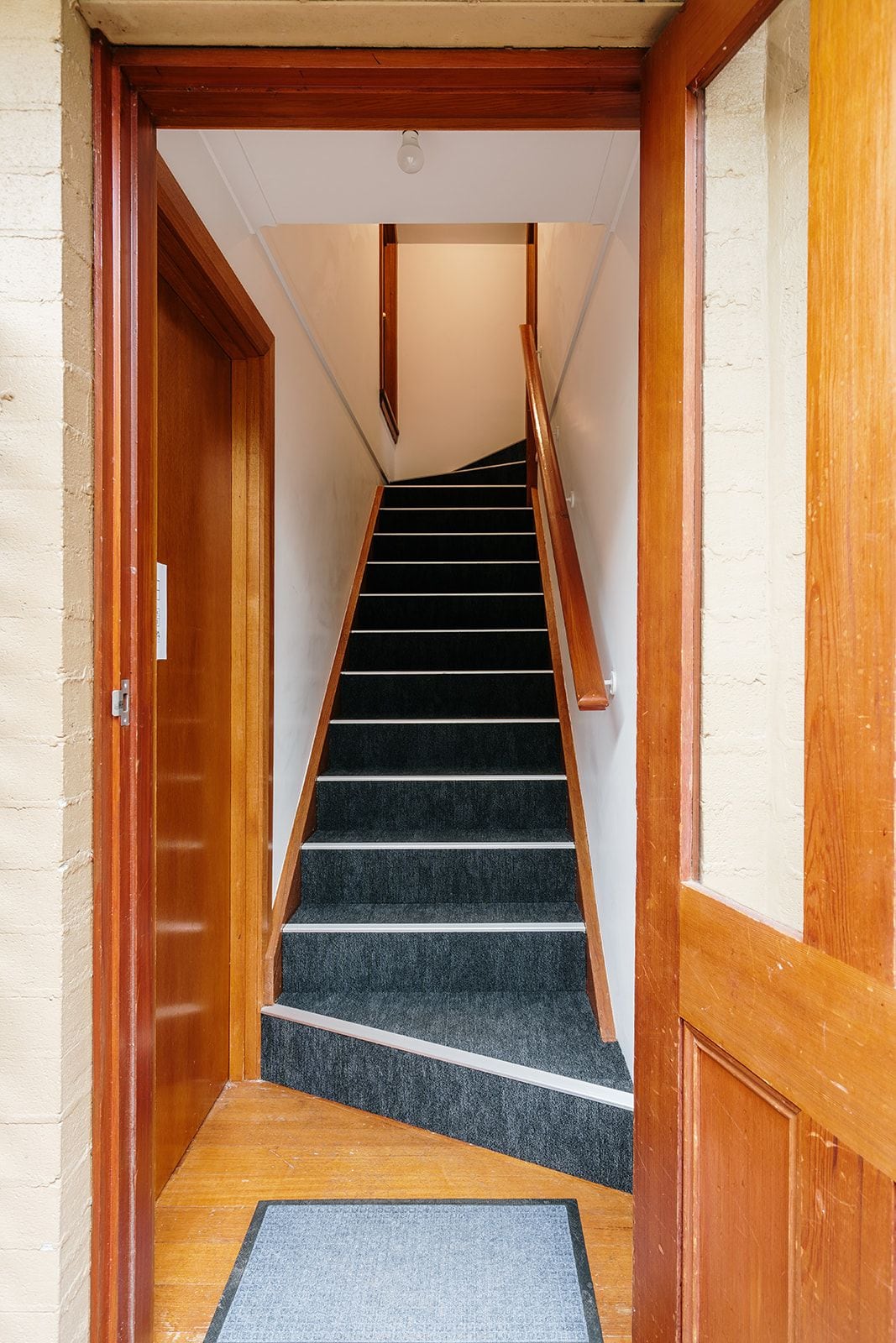 Una escalera con barandillas de madera y piso alfombrado que conduce a un nivel superior.