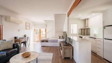 Un interior moderno con sala de estar, cocina y una escalera que sube a un dormitorio tipo loft.
