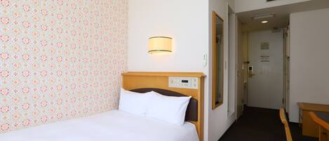 A hotel room with a bed, a wall-mounted control panel, a mirror, and a door leading to another room.