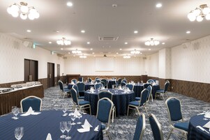 A conference room with round tables, blue chairs, and white linens.