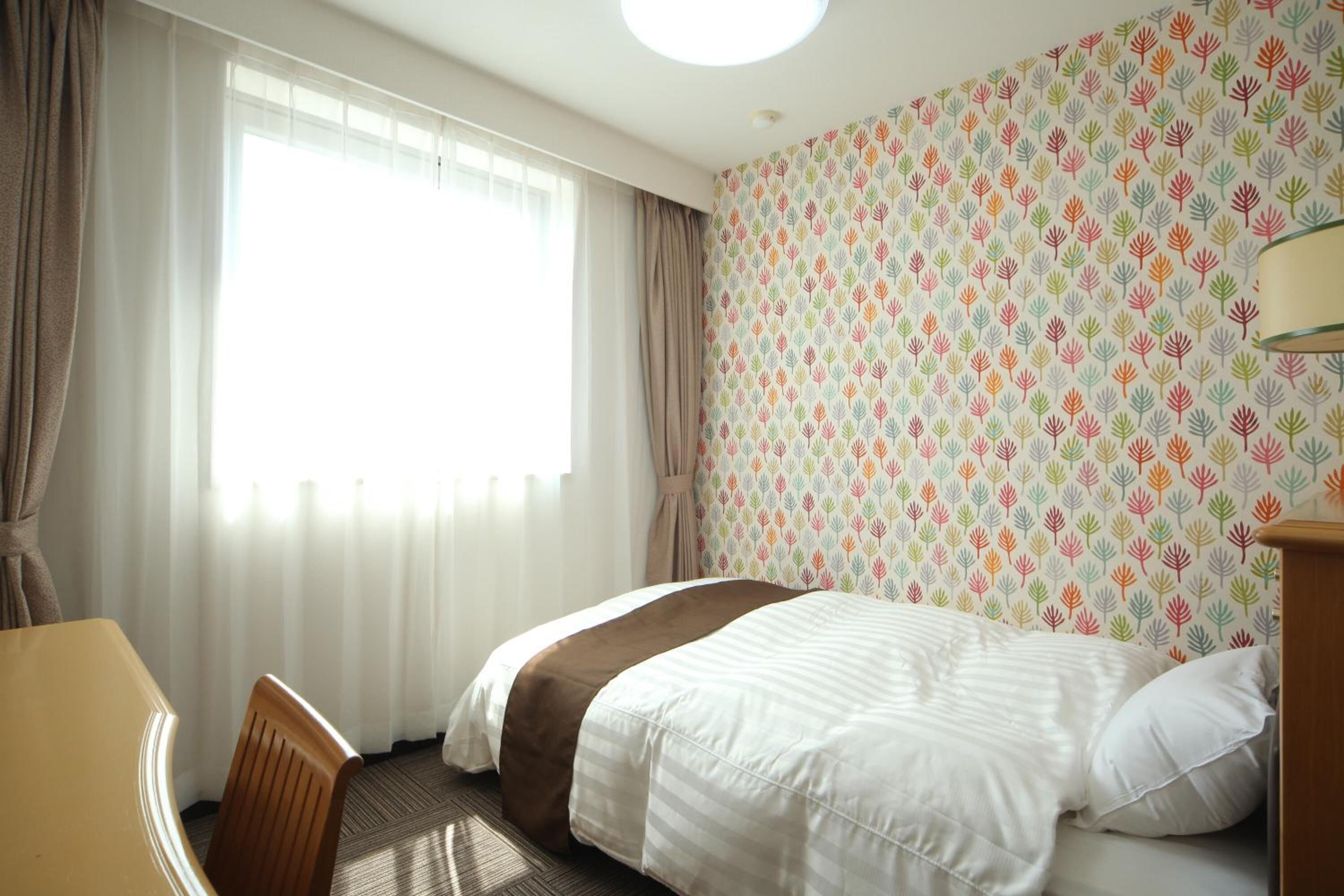 Een hotelkamer met een bed, een bureau en een raam met gordijnen.