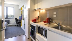 A modern kitchen with white cabinets, a stainless steel sink, and a microwave. - ECU Joondalup Village (Joondalup)
