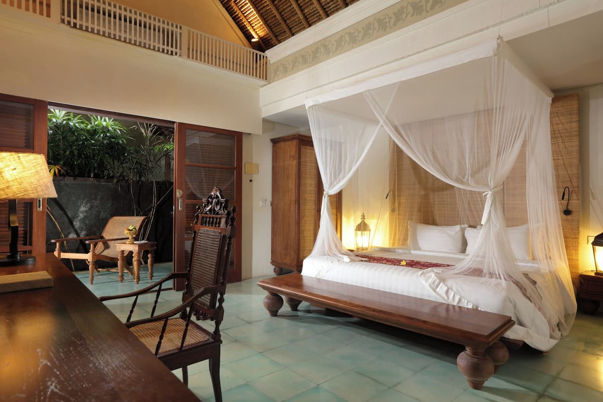A room with a four-poster bed, a wooden table, and a chair.