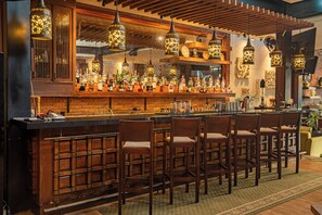 A bar with wooden bar stools, hanging lanterns, and a brick wall. - Plataran Ubud Hotel & Spa (Ubud)