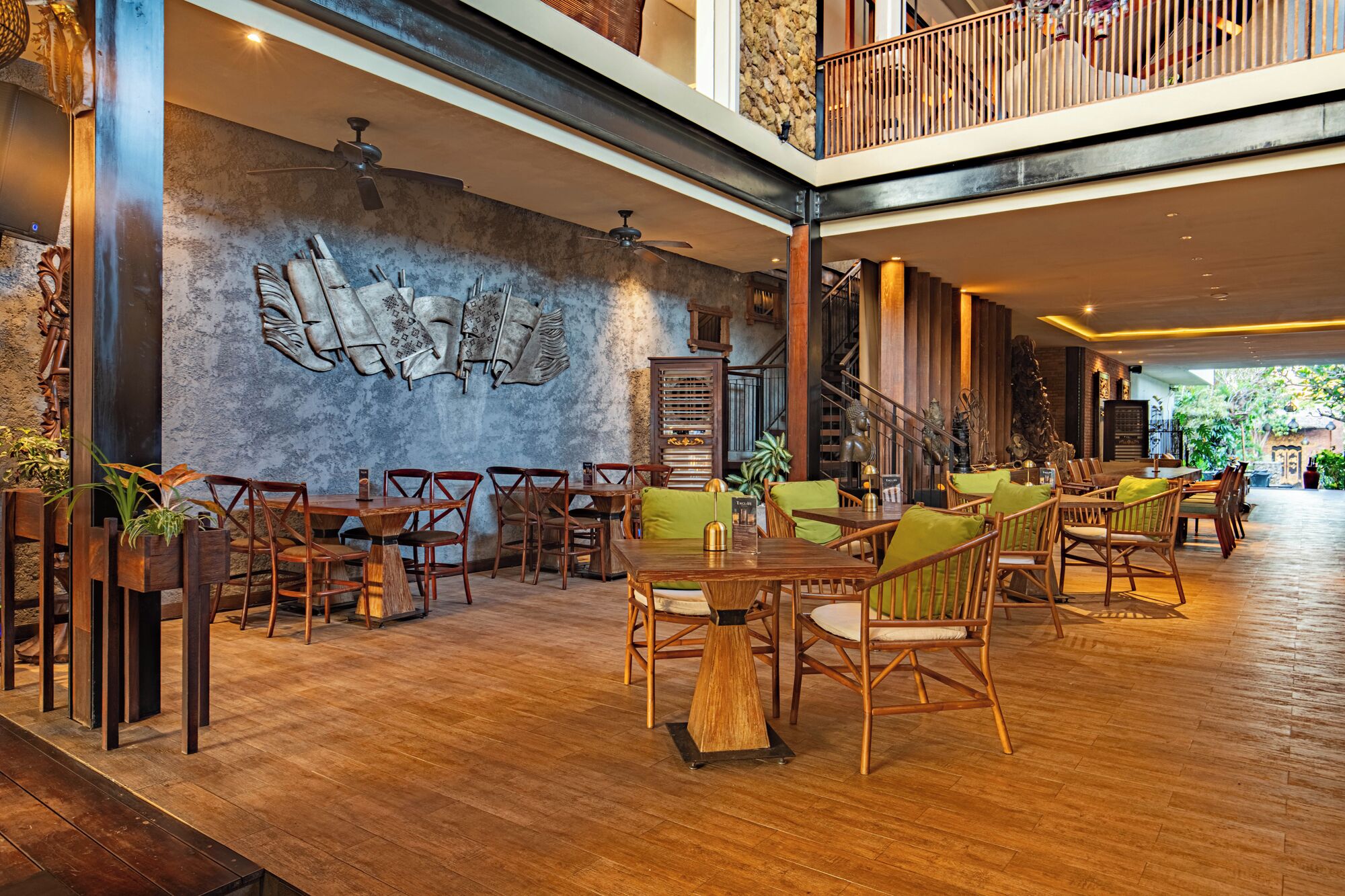 A spacious indoor area with wooden flooring, multiple seating arrangements, and a decorative wall.