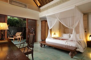 A room with a four-poster bed, a wooden bench, and a chair.