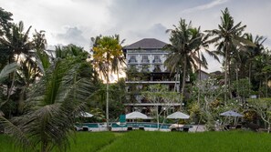 A multi-story hotel with a pool area, surrounded by lush greenery and palm trees. - Plataran Ubud Hotel & Spa (Ubud)