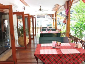 Un'area pranzo all'aperto con pavimento in legno, tovaglia a quadri rossa e vista sulla strada.