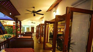 Ein Hotelkorridor mit Holzboden, Deckenventilator und kariertem Tischläufer in Rot und Karo.