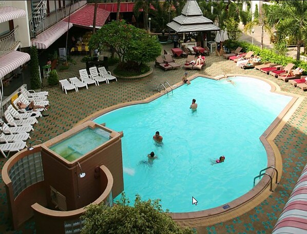 Una piscina con sillas de descanso y zona de hidromasaje.