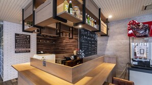 Interior de una cafetería con mostrador de madera, estanterías con bebidas, un menú en la pizarra y un anuncio de Coca-Cola.