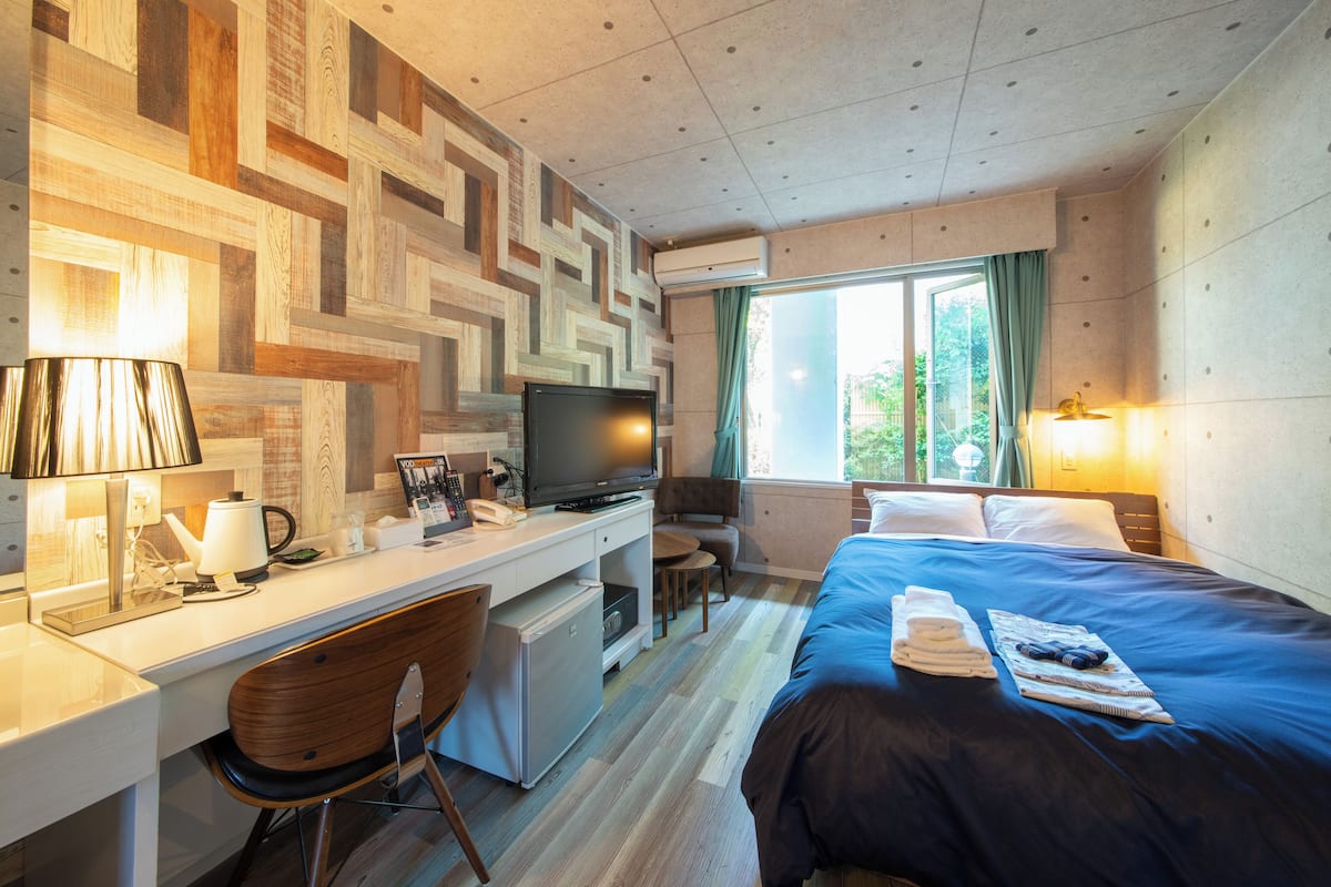 Habitación de hotel con escritorio, televisión y cama con toallas y un libro.