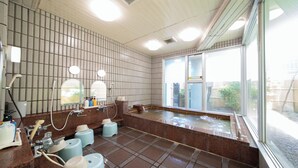 Un baño moderno con una bañera amplia, varios lavamanos y vistas al exterior a través de amplias ventanas.